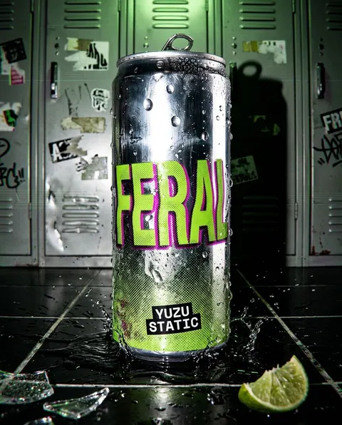 The same FERAL can on cracked black floor tiles in a corridor of school lockers, lit hard from one side.